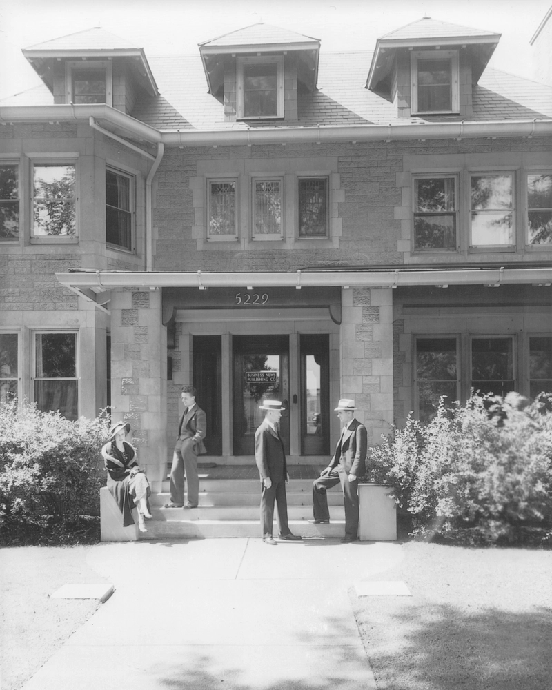 Black-and-white 1930s photo of BNP Media’s original office building with team members talking on the front steps